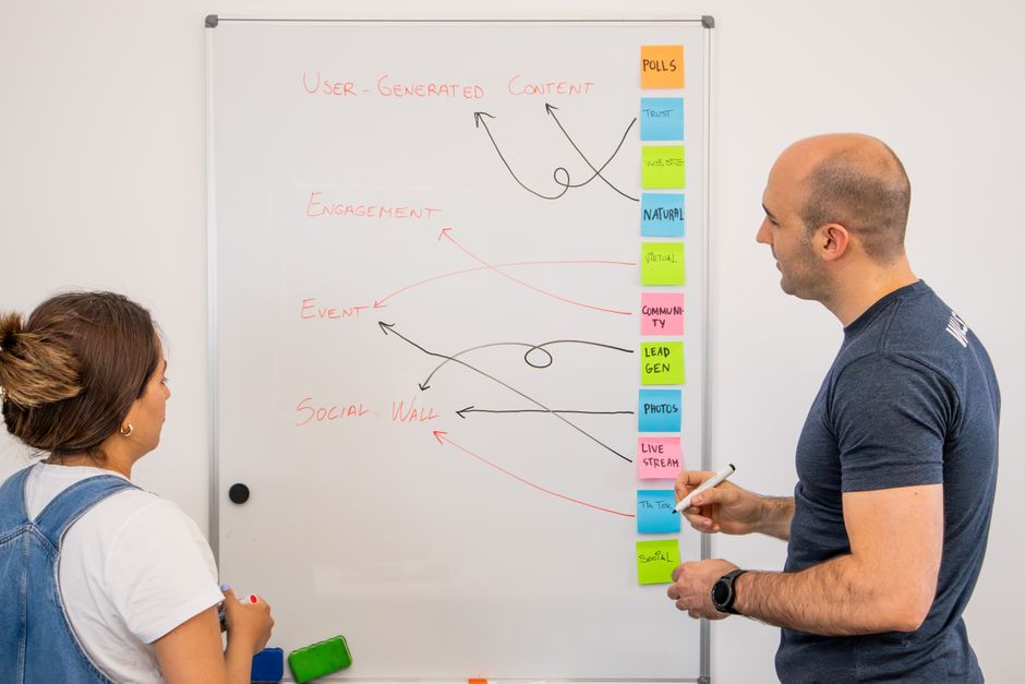 Dos colegas intercambian ideas en una pizarra durante una sesión de planificación técnica