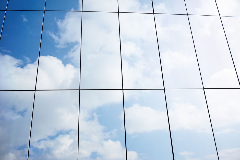 Reflejo de nubes en la fachada de cristal de un edificio moderno, arquitectura urbana.