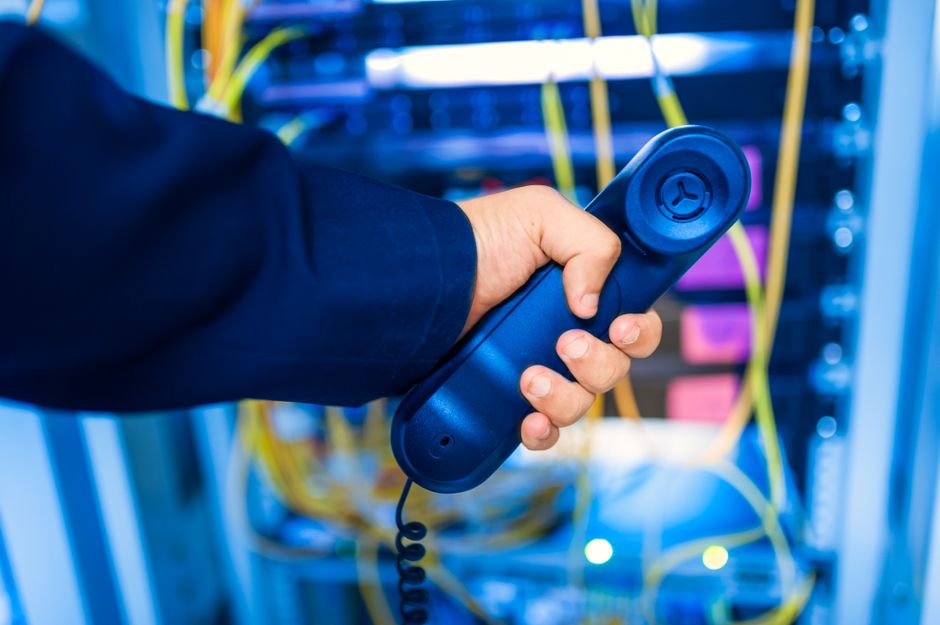 Mano sosteniendo un teléfono en una sala de servidores