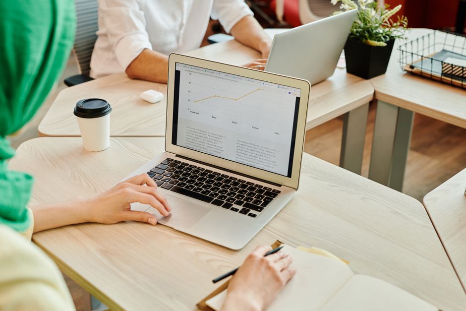 Espacio de trabajo moderno con personas usando laptops, enfocadas en análisis de datos en pantalla