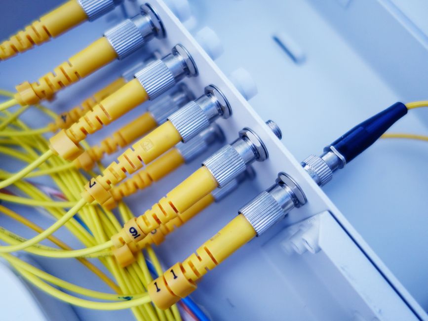 Primer plano de cables de fibra óptica amarillos en un servidor de red, mostrando transferencia de datos rápida