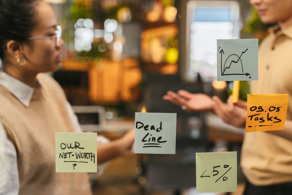 Reunión de equipo frente a una pared de vidrio con notas adhesivas de brainstorming