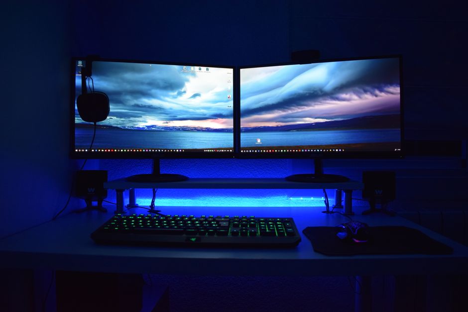 Doble monitor con iluminación azul en un escritorio de trabajo.